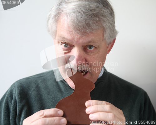 Image of senior man bites into chocolate rabbit 