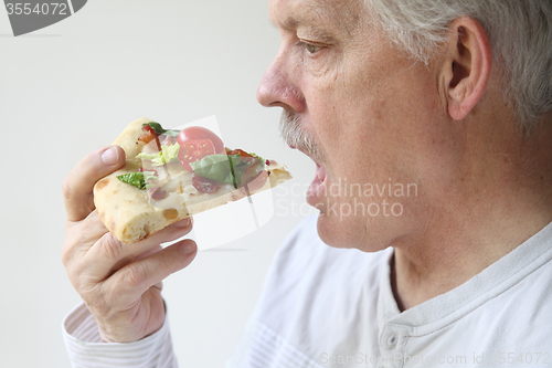 Image of man eats BLT pizza profile view 