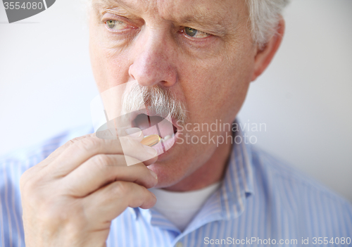 Image of man taking fish oil pill 