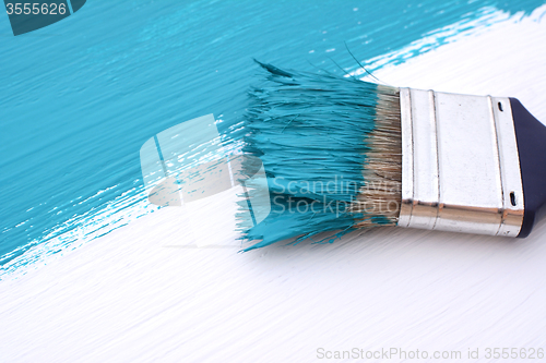 Image of Close-up of paintbrush painting a white board blue
