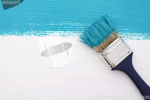 Image of Stripe of turquoise paint with a paintbrush on white