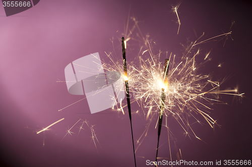 Image of Burning sparklers on pink background