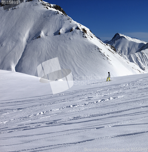 Image of Snowboarder downhill on off piste slope with newly-fallen snow