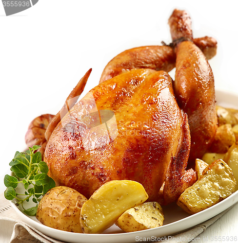 Image of roasted chicken with potatoes on white plate