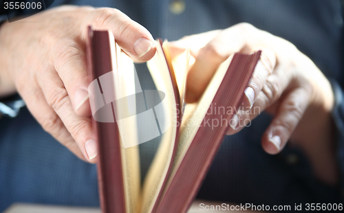 Image of Man turns pages of book.