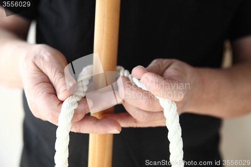 Image of man with rope and wood pole