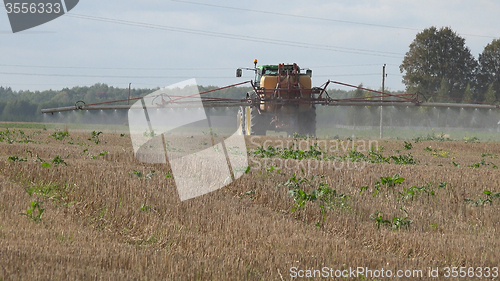 Image of Tractor spray stubble field with herbicide chemicals in autumn 