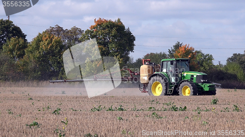 Image of Tractor spraying stubble field with herbicide chemicals in autumn 