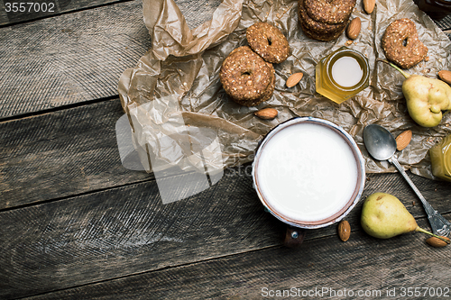 Image of Almonds pears Cookies and milk on wooden table