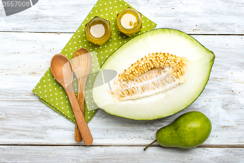 Image of Cut melon green pear and honey on white board