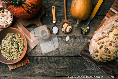 Image of Rustic style pumpkins with bread and seeds on wood