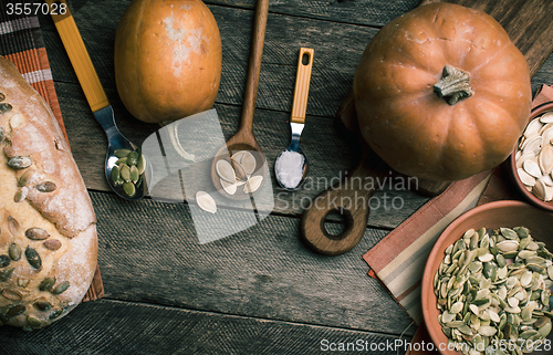 Image of Rustic pumpkins and bread with seeds on wood