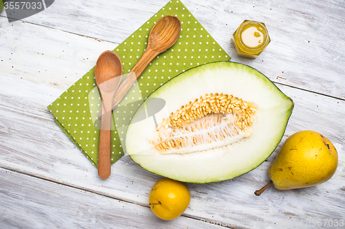 Image of Half cut melon with honey and pears in rustic style