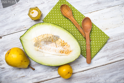 Image of Melon with honey and two yellow pears on wood