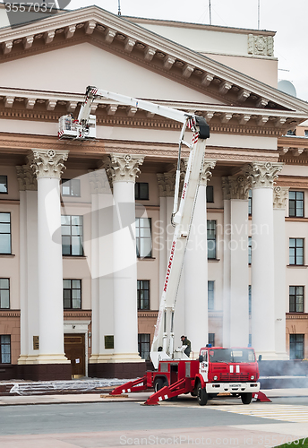 Image of Builders paint building facade by fire truck