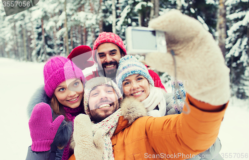 Image of smiling friends with camera in winter forest