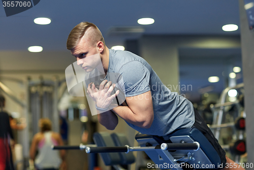 Image of young man flexing back muscles on bench in gym