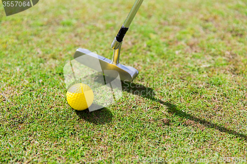 Image of close up of club and ball near hole on golf field