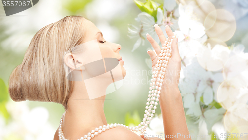 Image of woman with pearl necklace over cherry blossom