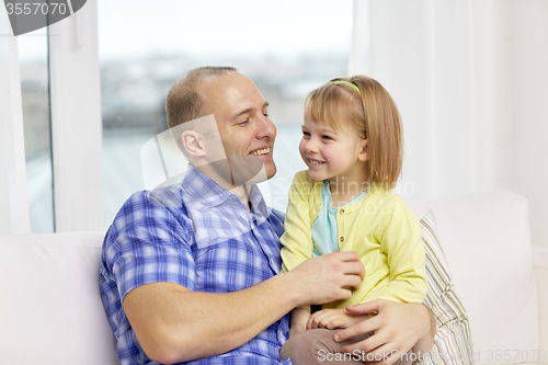 Image of happy father and daughter sitting on sofa at home