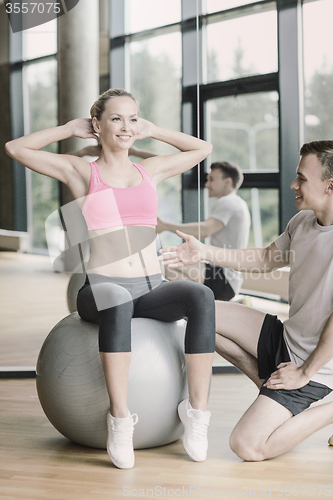 Image of smiling man and woman with exercise ball in gym