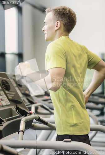 Image of smiling man exercising on treadmill in gym