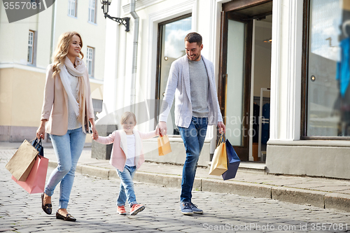 Image of happy family with child and shopping bags in city