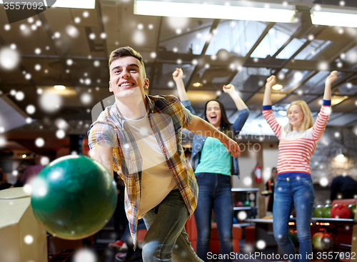 Image of happy young man throwing ball in bowling club