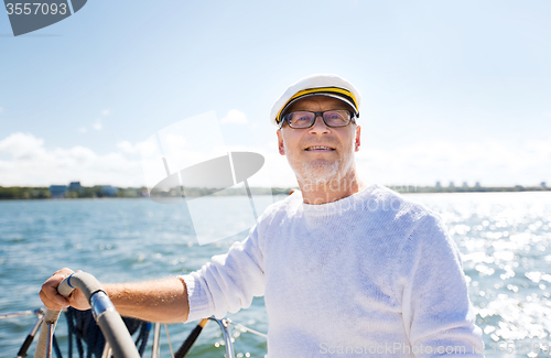 Image of senior man at helm on boat or yacht sailing in sea