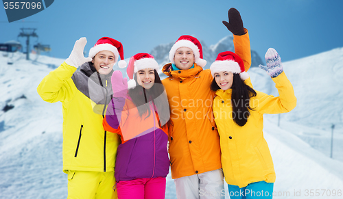 Image of happy friends in santa hats and ski suits outdoors