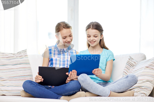 Image of happy girls with tablet pc sitting on sofa at home