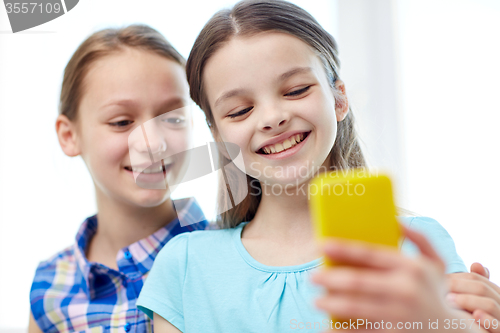 Image of happy girls with smartphone taking selfie at home