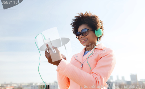 Image of happy young woman with smartphone and headphones