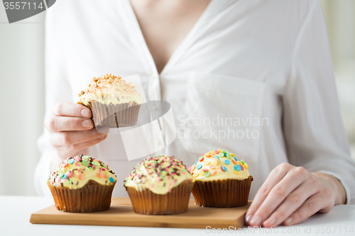 Image of close up of woman with glazed cupcakes or muffins