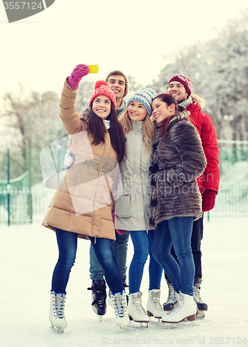 Image of happy friends with smartphone on ice skating rink