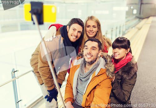 Image of happy friends with smartphone on skating rink
