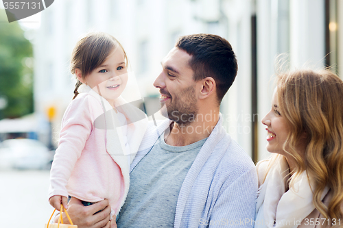 Image of happy family with child and shopping bags in city