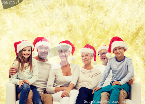 Image of happy family in santa helper hats sitting on couch