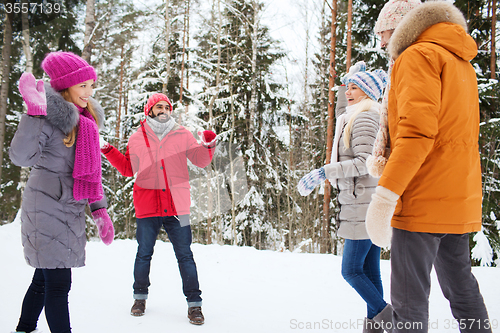 Image of happy friends playing snowball in winter forest