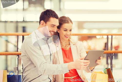 Image of couple with tablet pc and shopping bags in mall