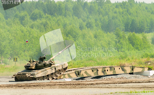 Image of T-80 tank drives on bridge induced through obstacle