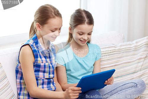 Image of happy girls with tablet pc sitting on sofa at home