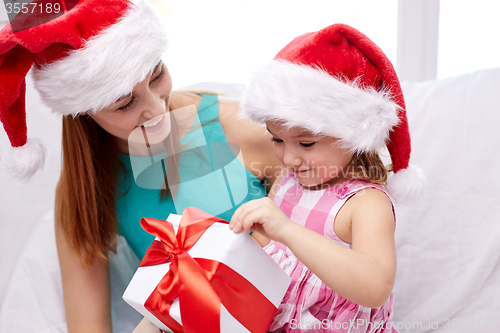 Image of happy mother and child in santa hats with gift box