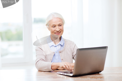 Image of happy senior woman with laptop at home