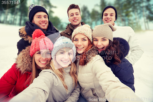 Image of group of smiling friends taking selfie outdoors