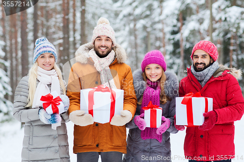 Image of happy friends with gift boxes in winter forest