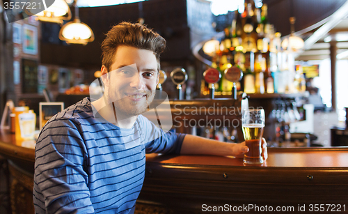 Image of happy man drinking beer at bar or pub