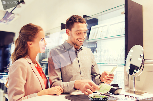 Image of happy couple paying for purchase in store