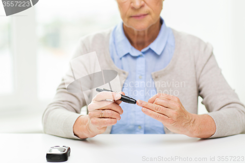 Image of senior woman with glucometer checking blood sugar