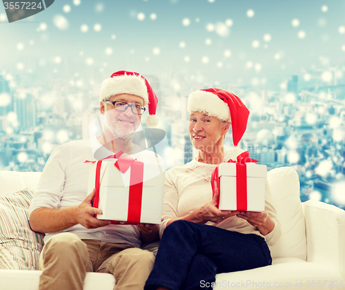 Image of happy senior couple in santa hats with gift boxes